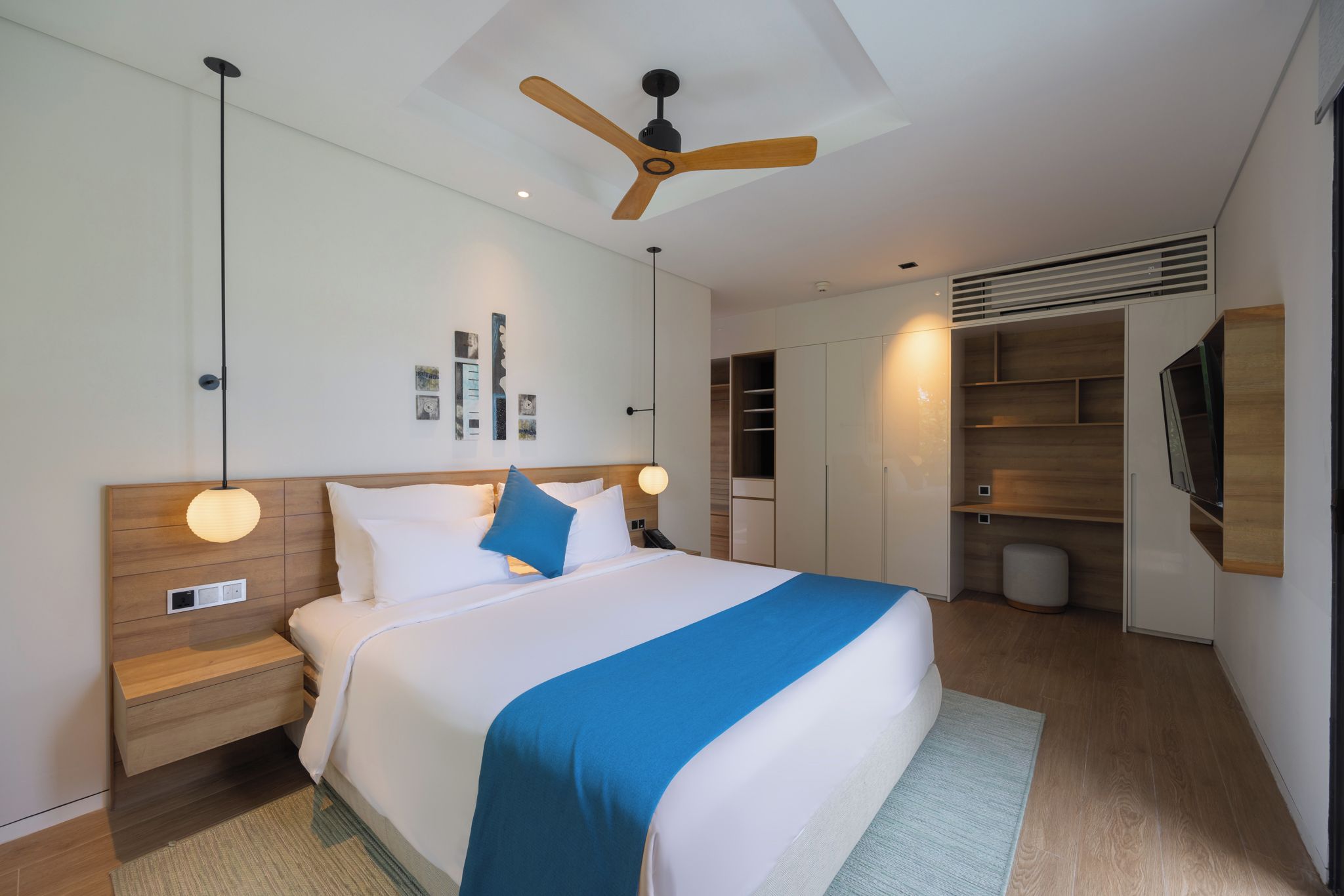Une chambre d’hôtel moderne équipée d’un grand lit, d’un ventilateur de plafond, d’une armoire et d’un téléviseur.