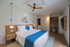A modern hotel room with a large bed, a ceiling fan, a wardrobe, and a television.
