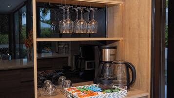 A kitchen counter with a coffee maker, glassware, and a tray of snacks.