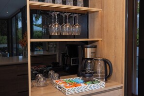 Una encimera de cocina con una cafetera, cristalería y una bandeja de aperitivos.