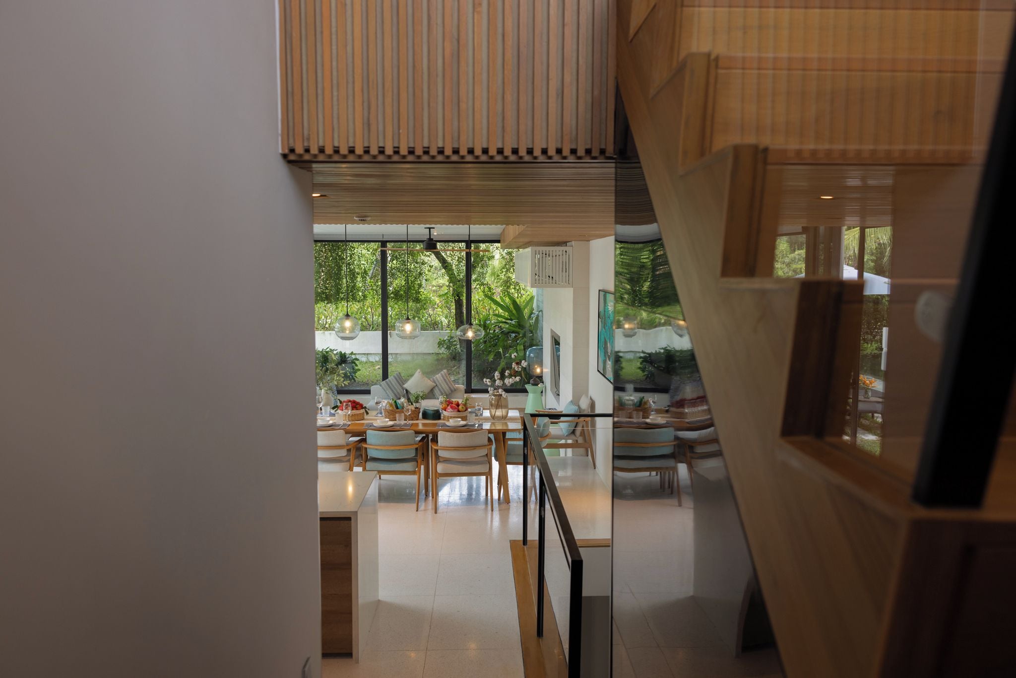 A modern interior with a dining area, large windows, and a staircase.