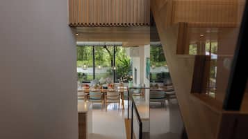 A modern interior with a dining area, large windows, and a staircase.