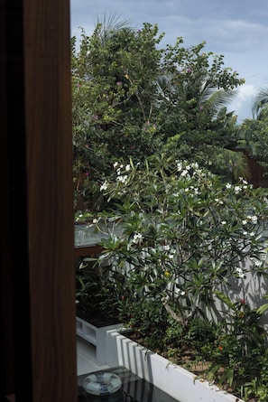 A view of a balcony with a variety of plants and flowers, a glass table, and a white wall. - Sailing Pool Villas & Resort Phu Quoc (Phu Quoc)