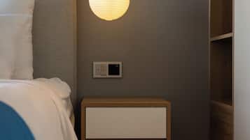 A bedroom with a bed, bedside table, nightstand, and a wall-mounted light fixture.
