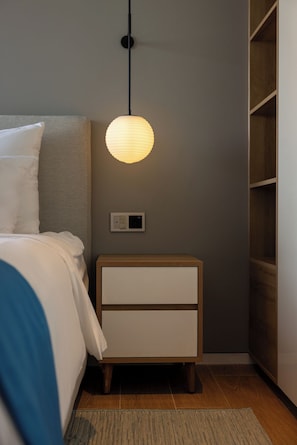 A bedroom with a bed, bedside table, nightstand, and a wall-mounted light fixture. - Sailing Pool Villas & Resort Phu Quoc (Phu Quoc)
