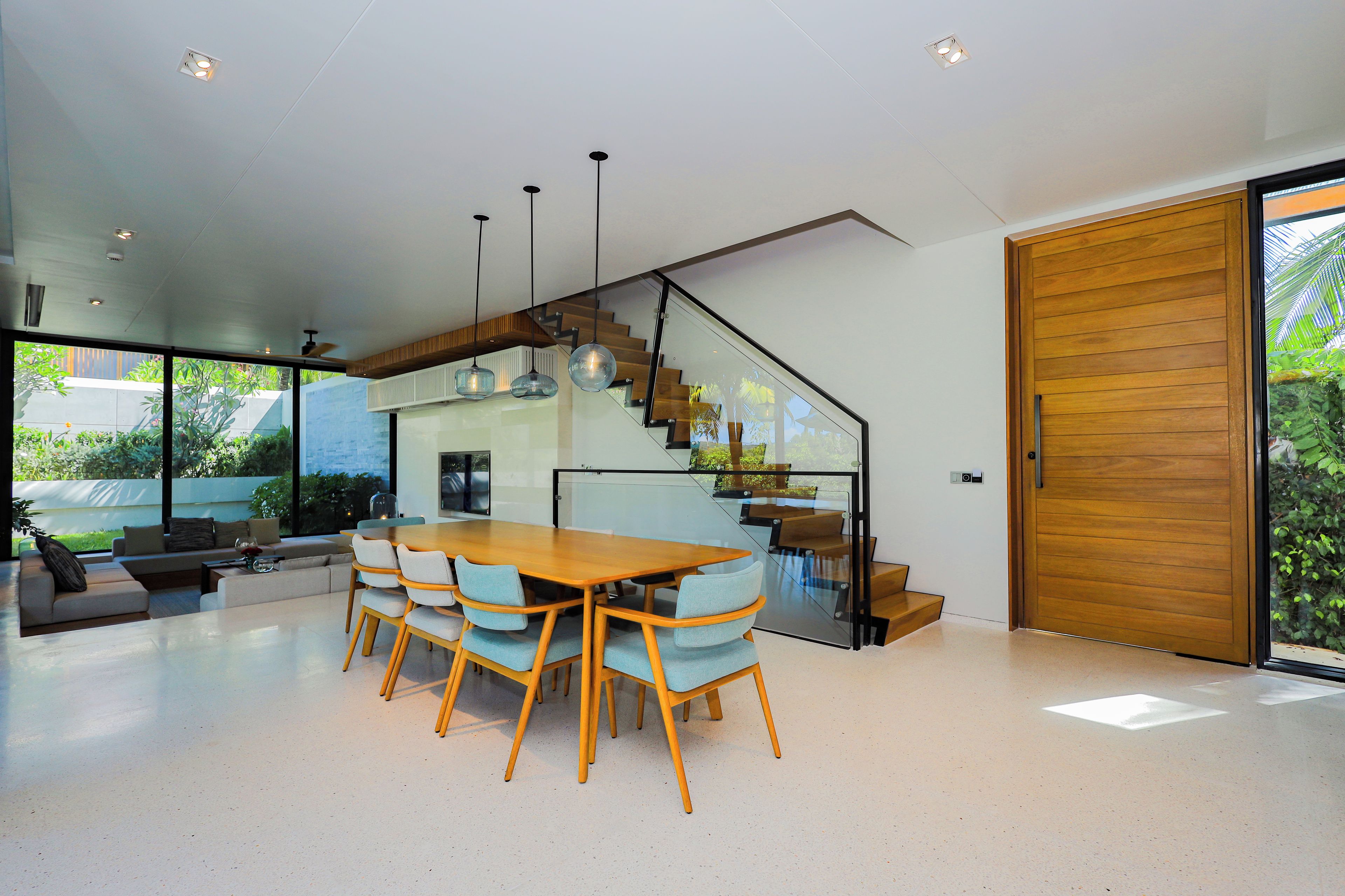 Un interior moderno con zona de comedor, escalera y grandes puertas correderas de vidrio.