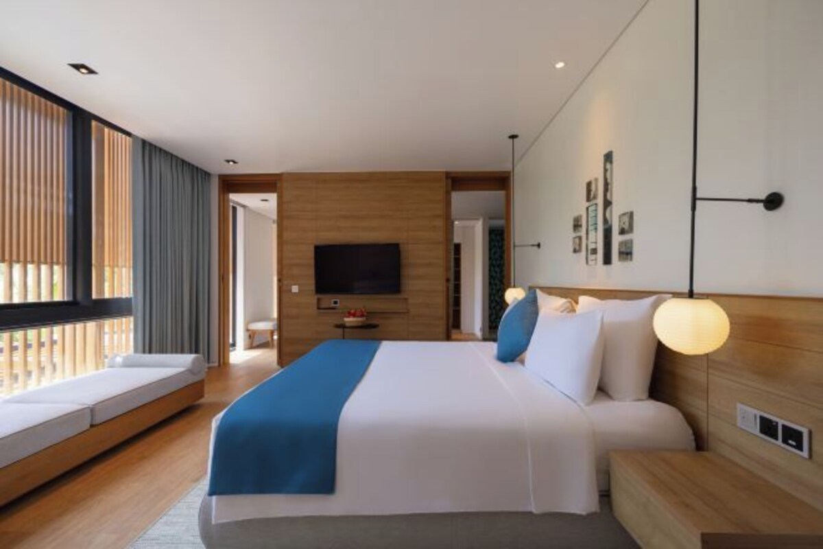 Une chambre d’hôtel moderne avec un grand lit, une télévision et un balcon.