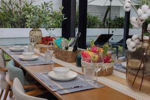 A dining table set with plates, glasses, and baskets containing fruits and flowers.