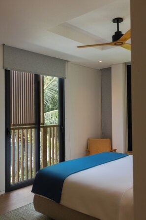 A hotel room with a bed, a ceiling fan, a window with blinds, and a view of palm trees. - Sailing Pool Villas & Resort Phu Quoc (Phu Quoc)