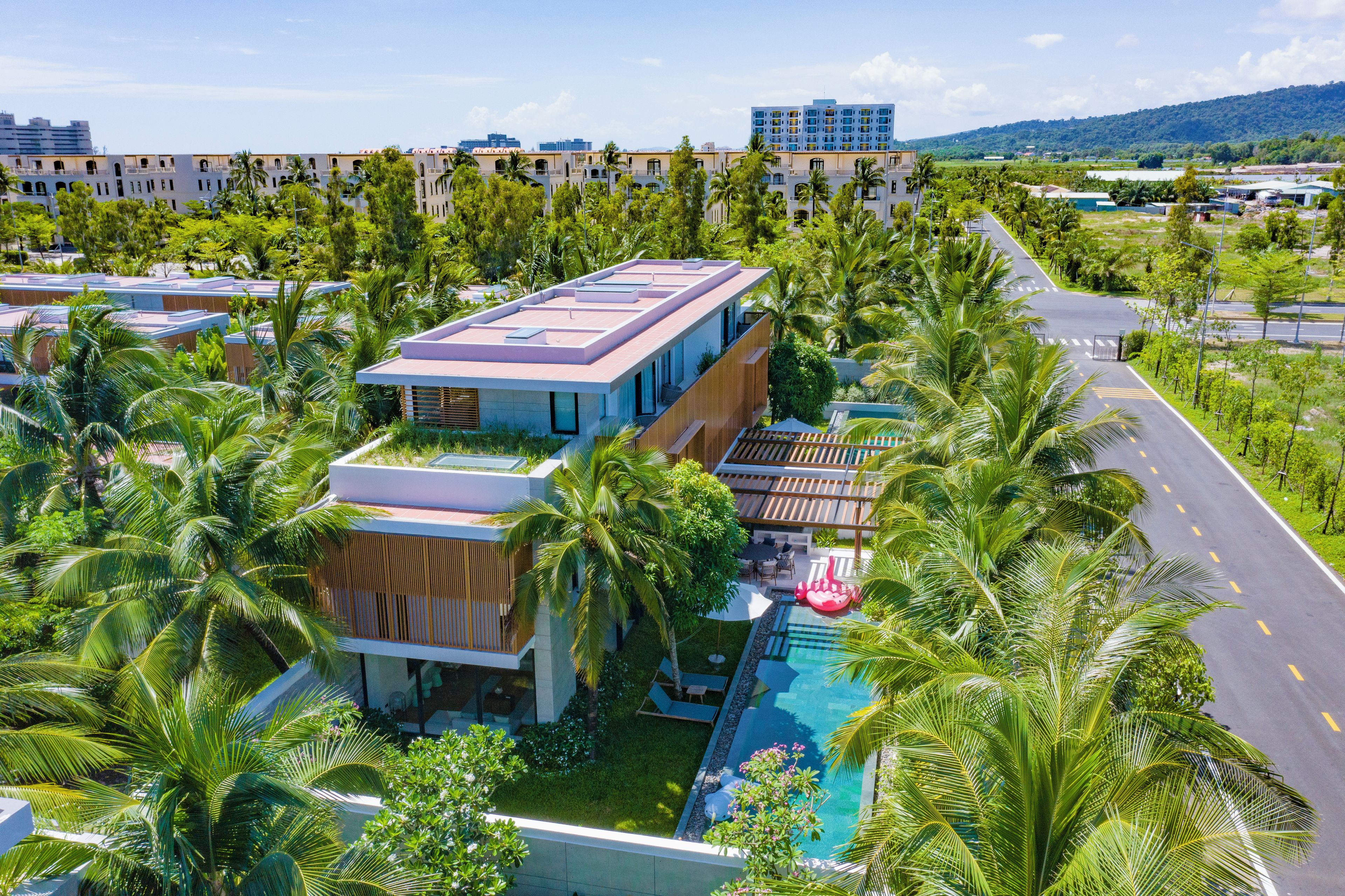 Un hotel moderno con piscina en la azotea, rodeado de exuberante vegetación y palmeras.