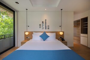 Una habitación de hotel moderna con una cama grande, mesitas de noche, un teléfono y vistas a zonas verdes por la ventana.