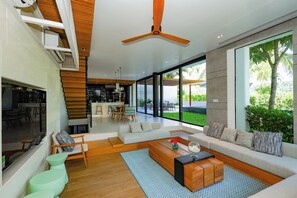 A modern living room with a large window, a ceiling fan, and a seating area with a coffee table.