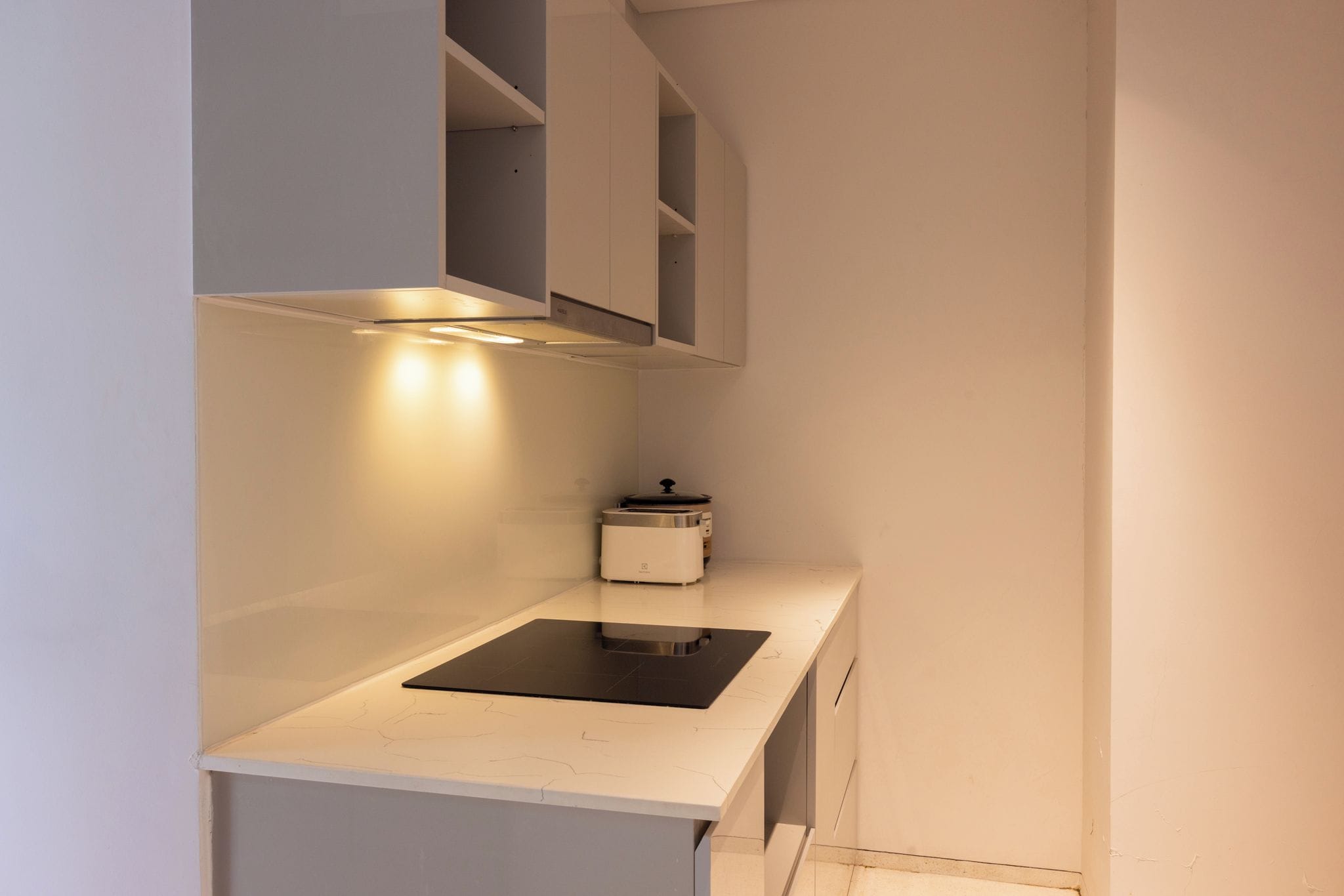 Una cocina compacta con estufa integrada, tostadora y un mueble sobre la encimera.