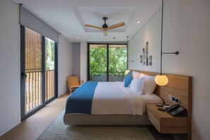 A modern bedroom with a large bed, a ceiling fan, a bedside table with a lamp, and a view of greenery through the window.