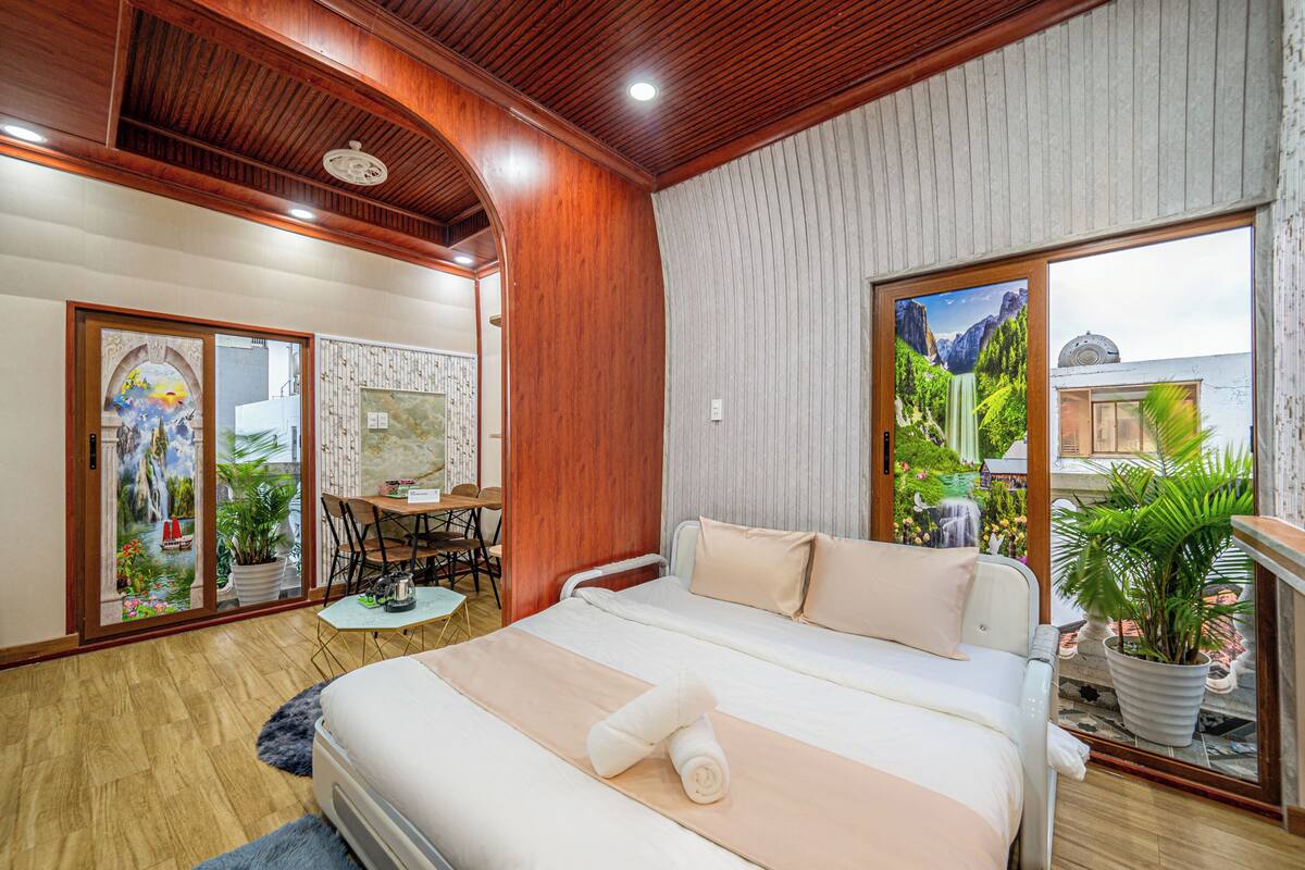 A hotel room with a bed, a desk, and a view of a garden.
