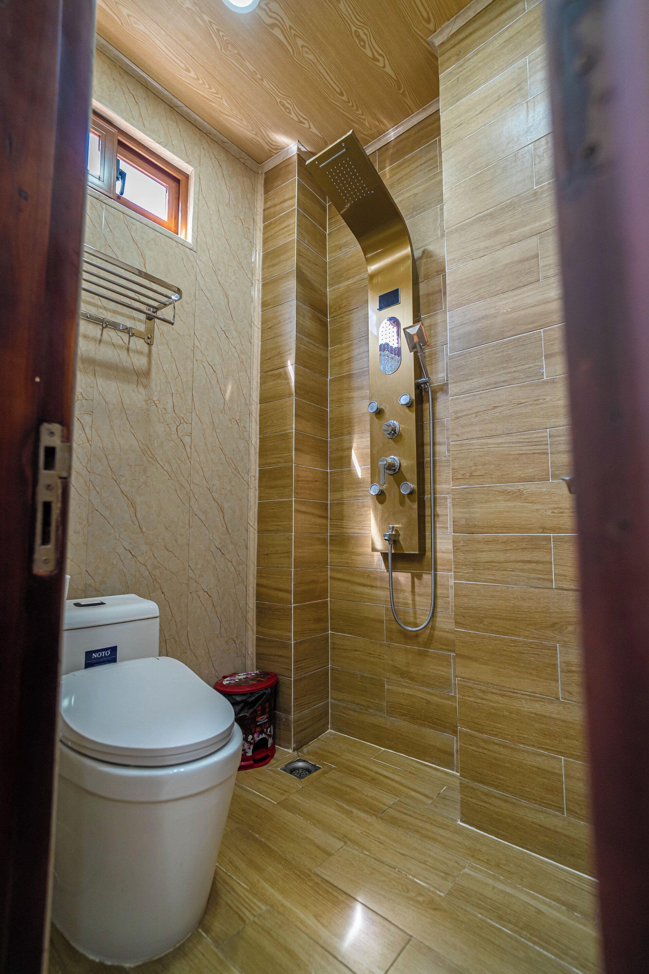 Un baño con ducha, inodoro y una ventana pequeña.