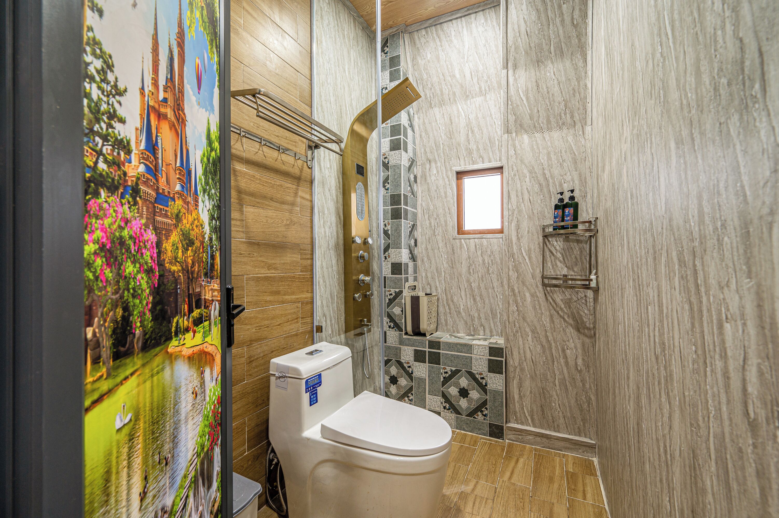 A bathroom with a toilet, shower, and a decorative mural of a castle.