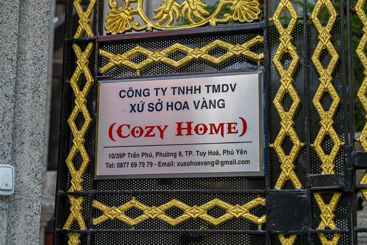 A sign for a property named "COZY HOME" with contact information and location details.