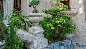 A courtyard with ornate columns, a stone fountain, and a window with a wooden frame. - Cozrum - Cozy Home Phú Yên (Tuy Hoa)