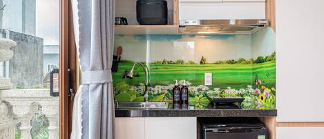 A compact kitchen with a wooden ceiling, a built-in microwave, and a small refrigerator.