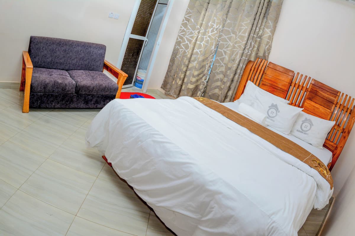 A bedroom with a bed, a wooden headboard, and a sofa.