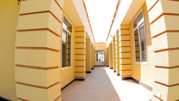 A corridor with a series of windows and doors, leading to a bright interior space. - Bezinda Lodge (Dodoma)