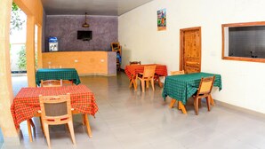 A dining area with tables and chairs, a counter, and a television. - Bezinda Lodge (Dodoma)