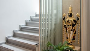 Un escalier avec une rampe en verre, une statue et une plante en pot.