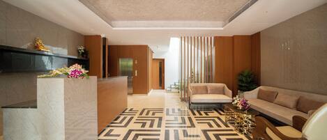 A modern lobby with a reception desk, a sofa, and a patterned floor.