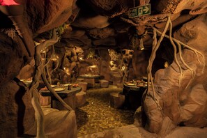 Un restaurant souterrain où les tables sont disposées contre les parois de la grotte, éclairées par un éclairage d’ambiance.