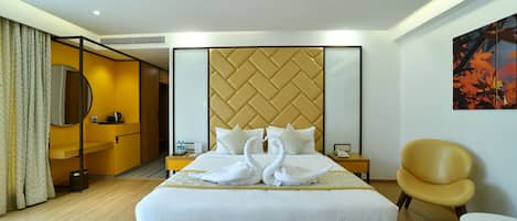 A hotel room with a large bed, a headboard with a herringbone pattern, a bedside table with a lamp, a chair, and a painting on the wall.
