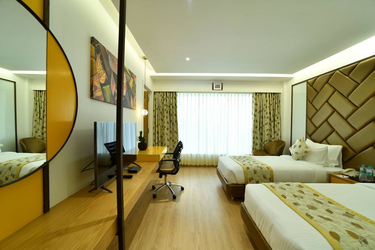 Hotelkamer met twee bedden, een bureau, een stoel, een spiegel en een raam met gordijnen.