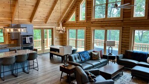 Un intérieur spacieux de chalet en bois, comprenant une cuisine, un coin repas et un salon.