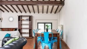A dining area with a wooden table and blue chairs, a sofa with green cushions, and a white wall with a decorative mirror. - Ghibellina Loft in Firenze (Florence)