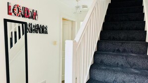A staircase with dark carpeting and white railings, leading to an upper floor. - House - Sleeps 8 - Parking - Garden (Peterborough)