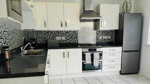 A modern kitchen with white cabinets, a stainless steel refrigerator, a gas stove, and a tiled backsplash. - House - Sleeps 8 - Parking - Garden (Peterborough)