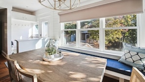 A bright kitchen with a large window, wooden table, and a built-in bench with cushions. - Downtown Annapolis Duke's House (Annapolis)