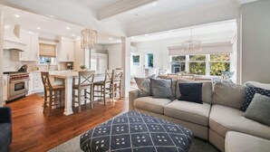 A spacious living area with a large sofa, a dining table with chairs, and a kitchen in the background. - Downtown Annapolis Duke's House (Annapolis)