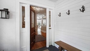 A hallway with a wooden bench, a white door, and a wall-mounted light fixture. - Downtown Annapolis Duke's House (Annapolis)
