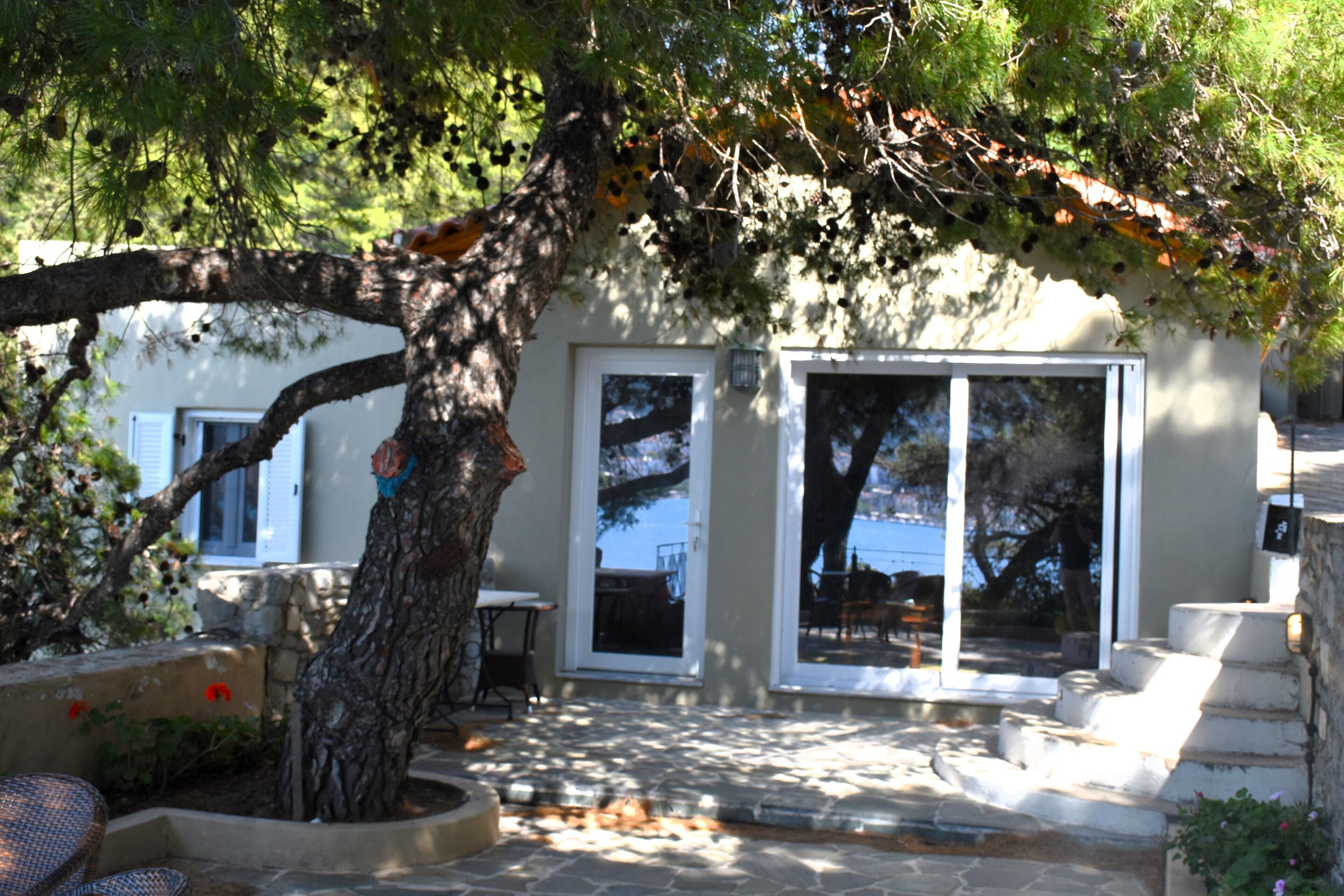 Une terrasse dallée de pierres, avec un arbre, une petite table et une chaise.