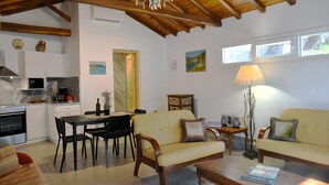 A well-lit living area with a dining table, sofa, and a kitchen in the background.