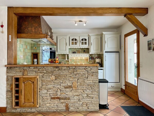 A kitchen with white cabinets, a stone island, and a wooden ceiling beam.
