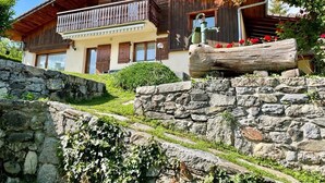 A traditional wooden chalet with a stone staircase leading to a wooden deck.