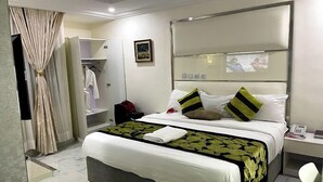 Ein Hotelzimmer mit einem großen Bett, einem Nachttisch, einem Kleiderschrank und einem Spiegel.