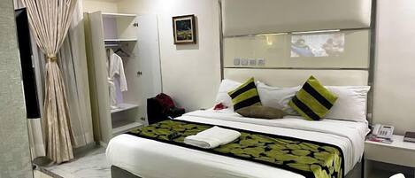 A hotel room with a large bed, a bedside table, a wardrobe, and a mirror.