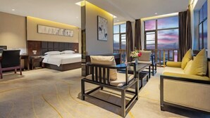 Quarto de hotel com uma cama, uma escrivaninha, um sofá, uma cadeira e vista para a cidade.