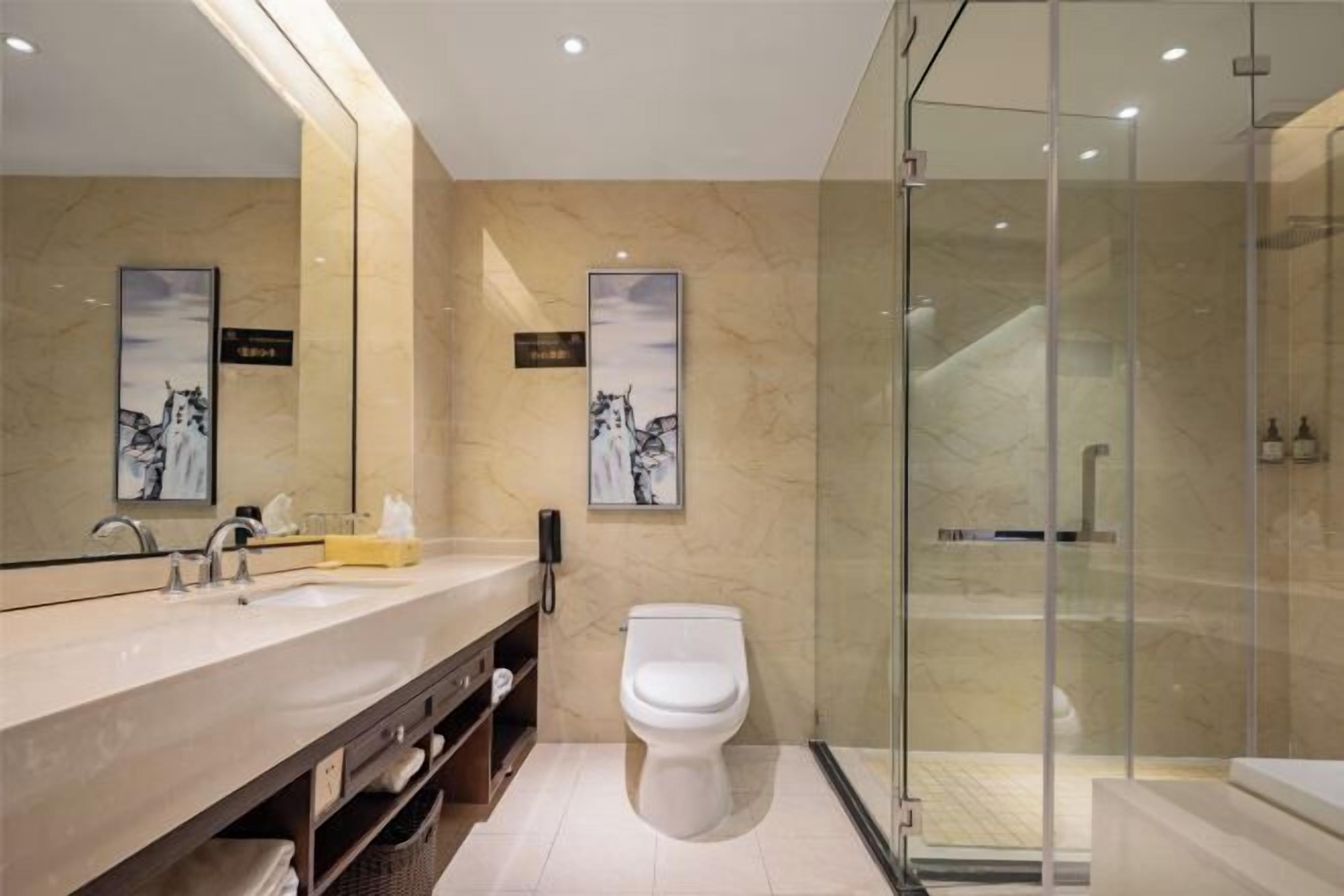 Un baño moderno con tocador de mármol, inodoro y ducha con cerramiento de vidrio.