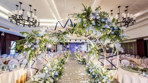 Local de casamento com arco de flores, mesas montadas para convidados e um candelabro.