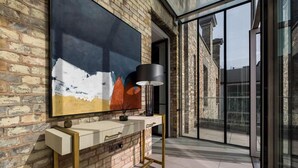A modern interior with a large abstract painting, a minimalist console table, and a view through large glass doors. - Penthouse Luxury in Covent Garden (London)