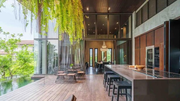 Een moderne keuken met een groot eiland, een bar en uitzicht op een zwembad.